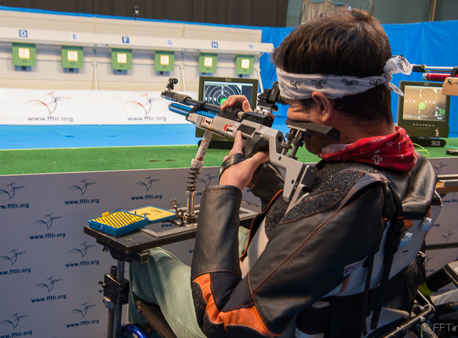 un tireur dans un fauteuil roulant avec une carabine adaptée